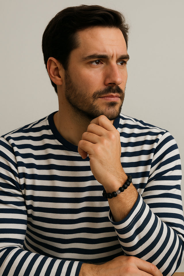 Homme portant un bracelet en quartz et onyx noir mat, posant pensivement en chemise rayée.