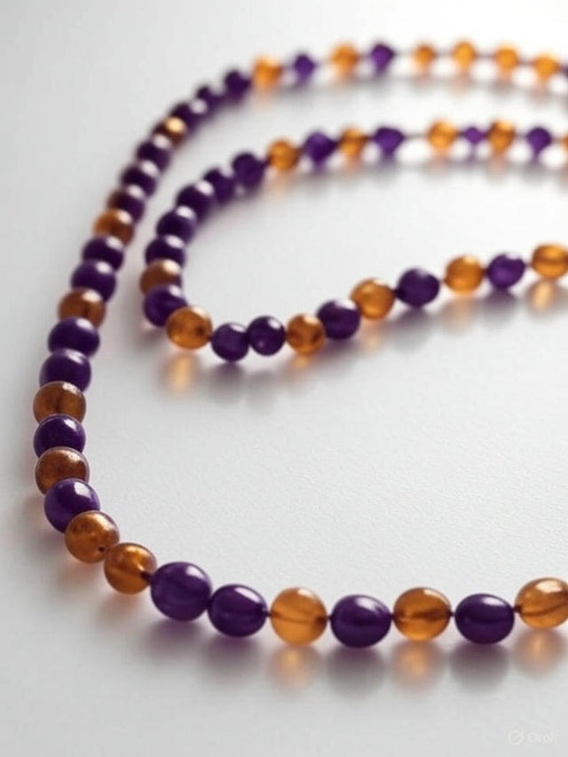Un collier avec des perles alternant violet et ambre repose sur une table blanche lisse, fond blanc.